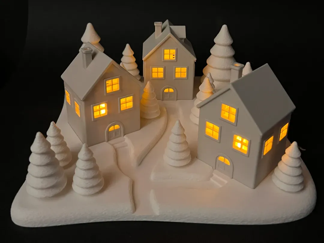 Village de Noël imprimé en 3D, fenêtres éclairées dans le noir
